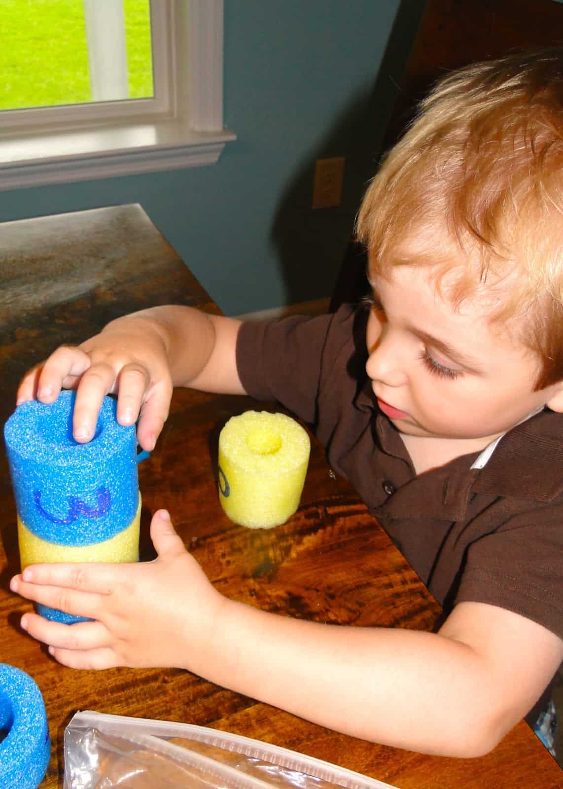 preschooler boy playing with pool noodles