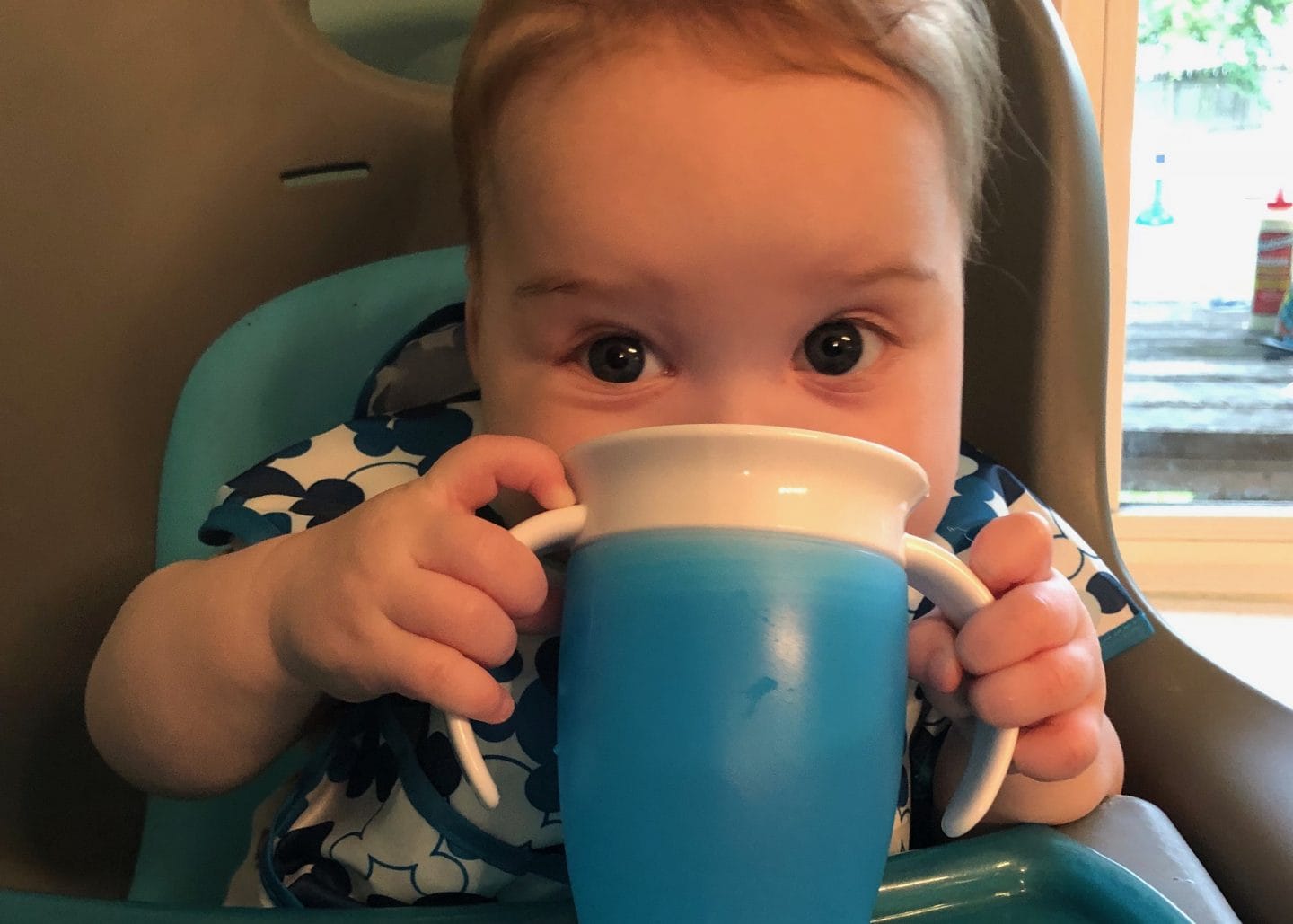 baby drinking from sippy cup using blw method in high chair