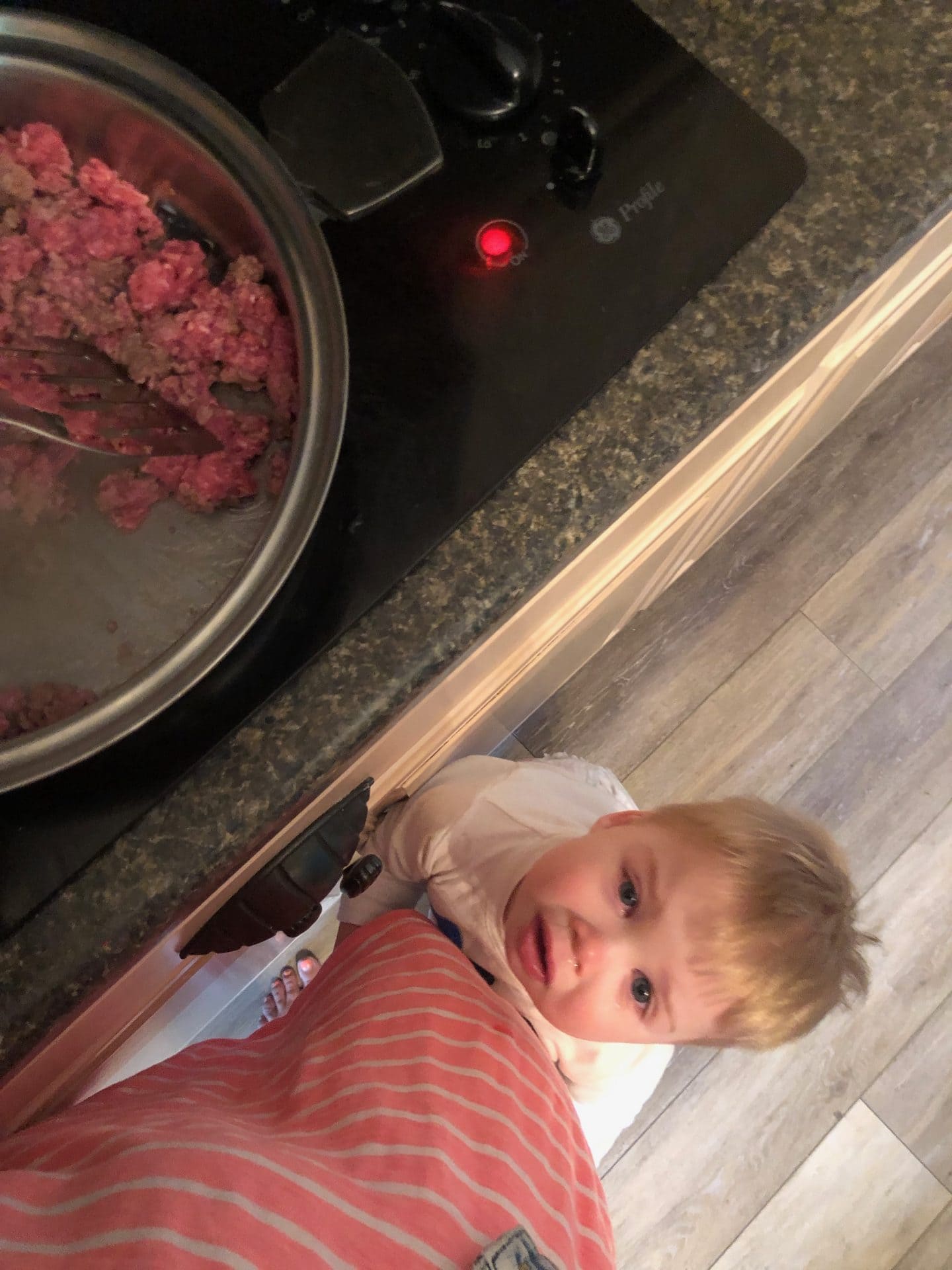 toddler clinging to mom leg while cooking