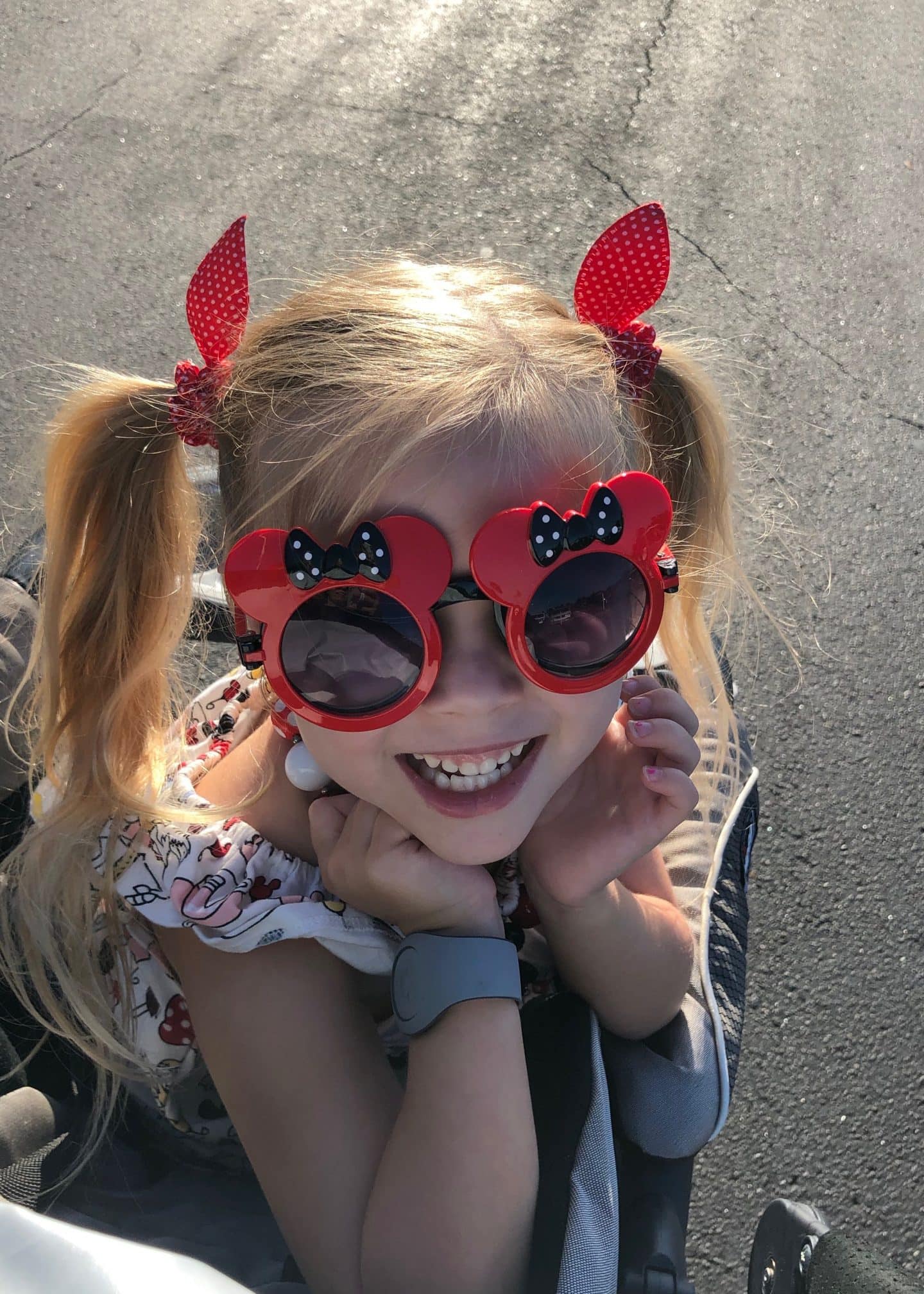 girl in magic kingdom parking lot with Minnie sunglasses