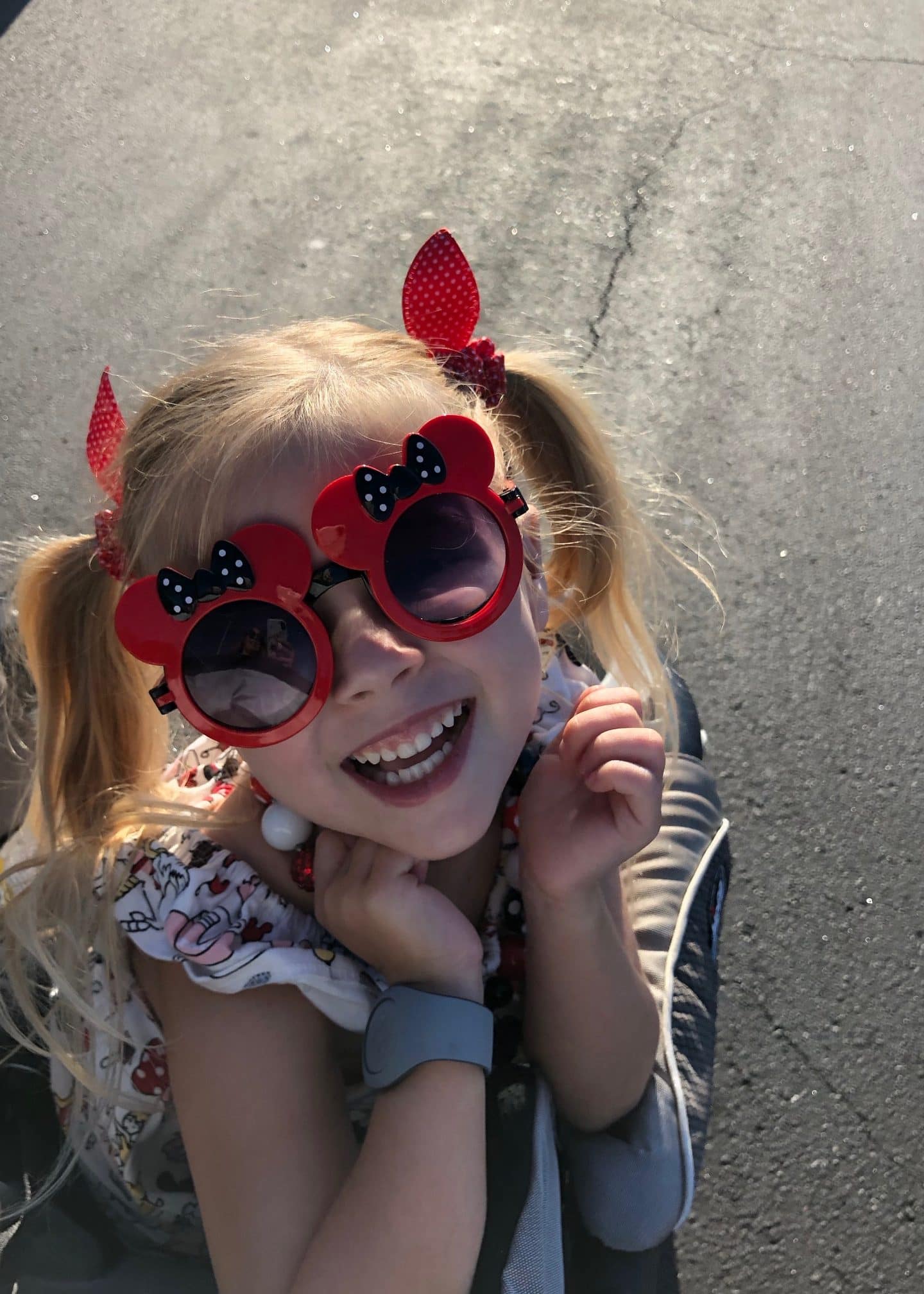 girl in magic kingdom parking lot with Minnie sunglasses