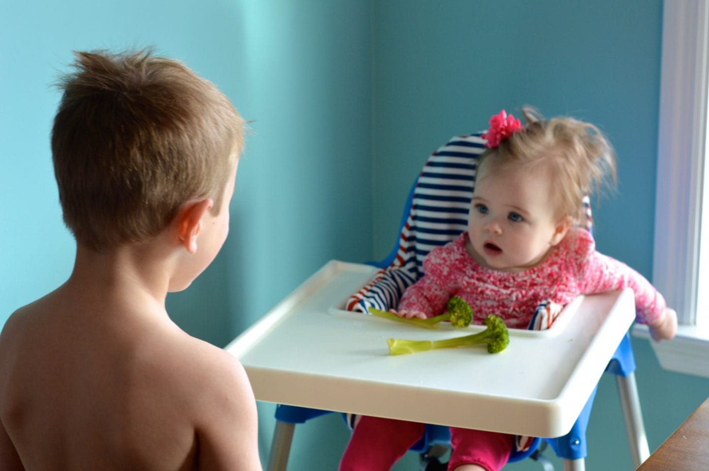 big brother helping baby sister eating solids for first time using baby led weaning