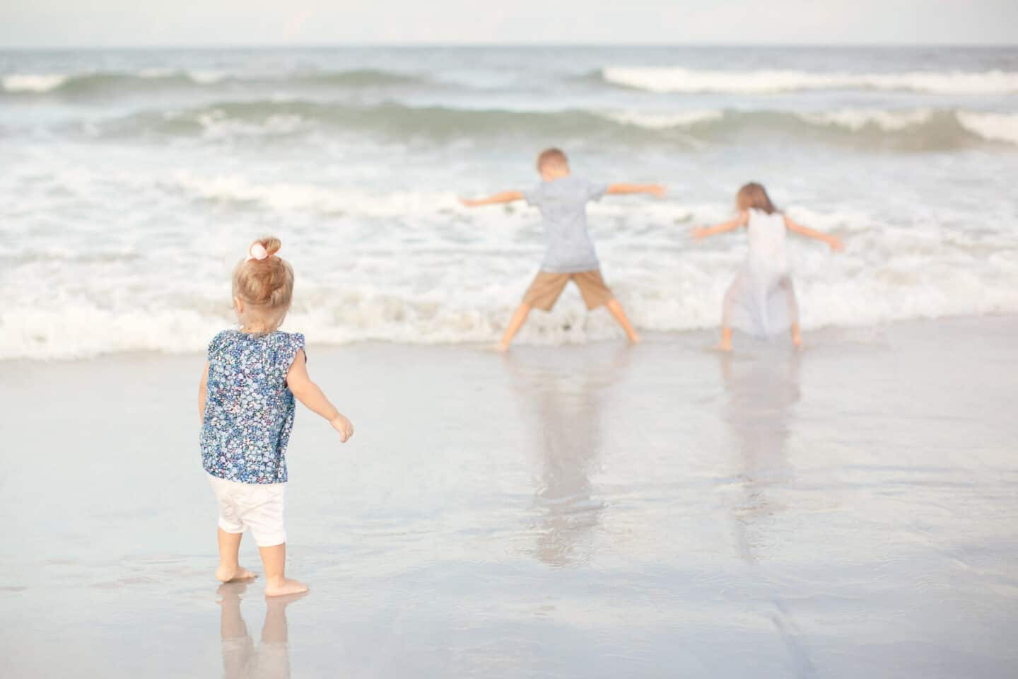 kids playing in ocean during a family photo session at the beach