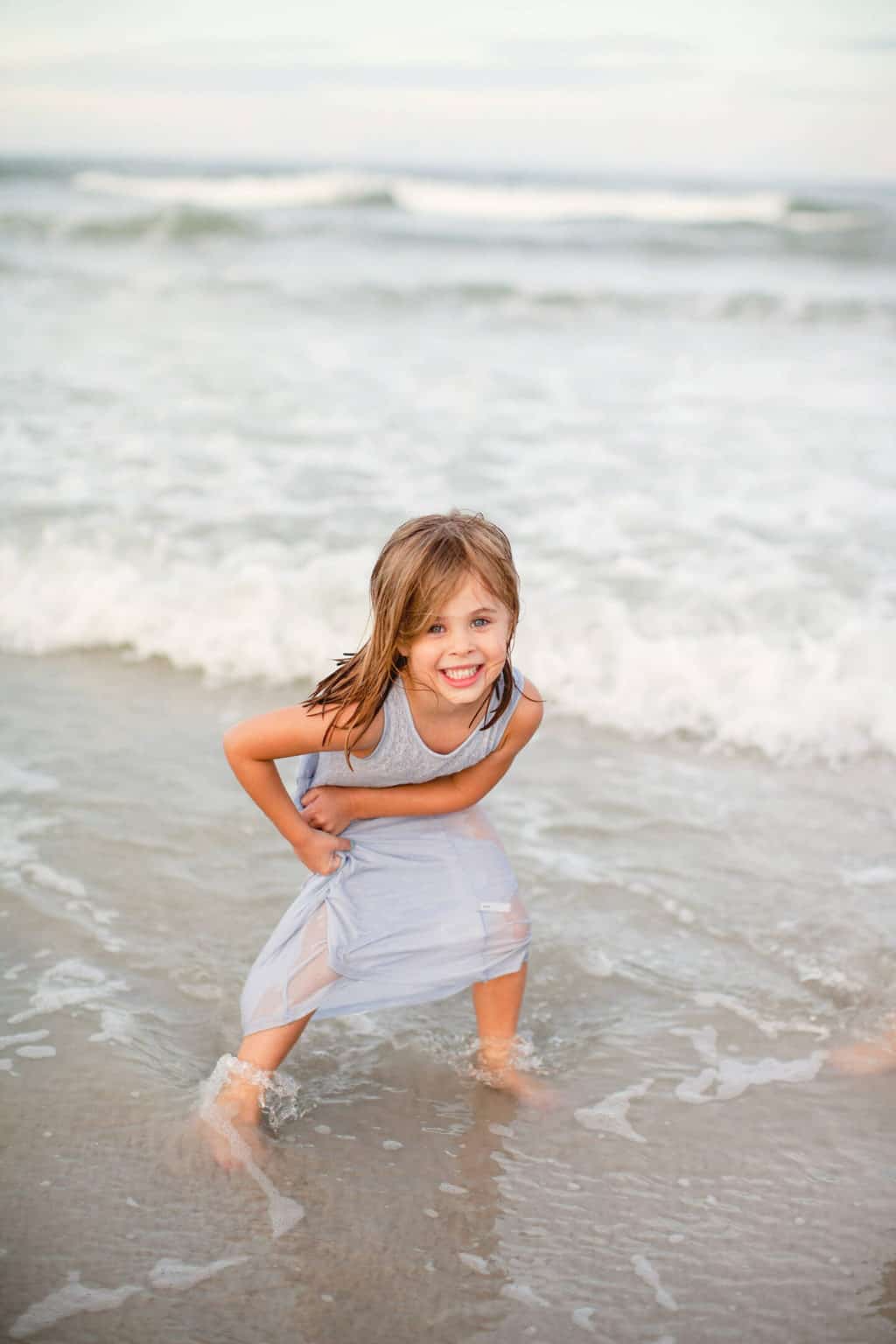 girl playing in ocean during family beach pictures