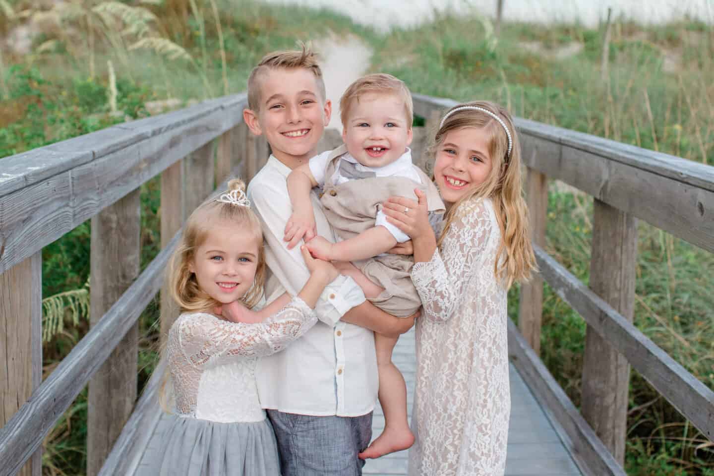 four kids at the beach taking family photos