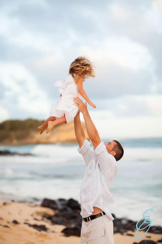 father throwing daughter in air during beach family photos