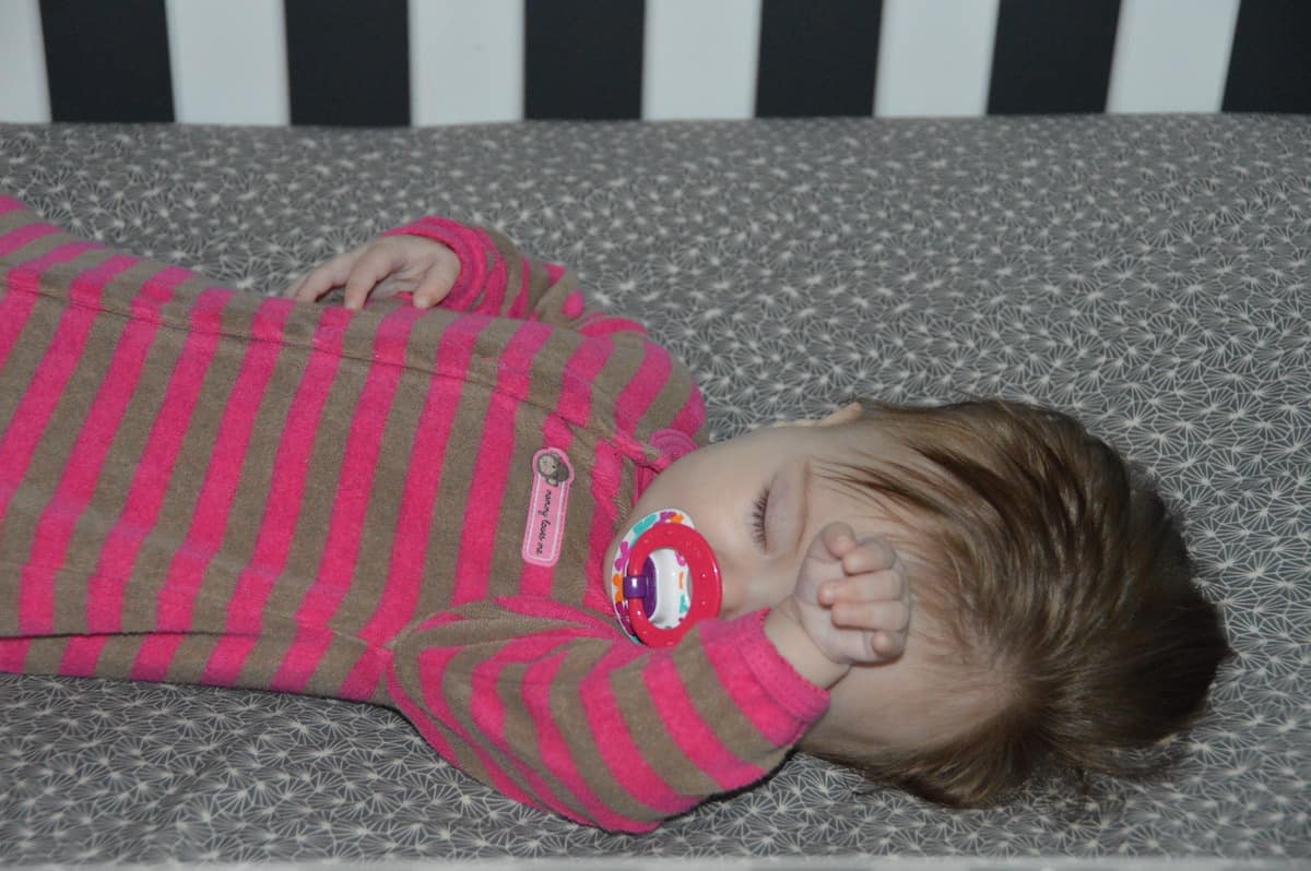 baby sleeping with pacifier in crib